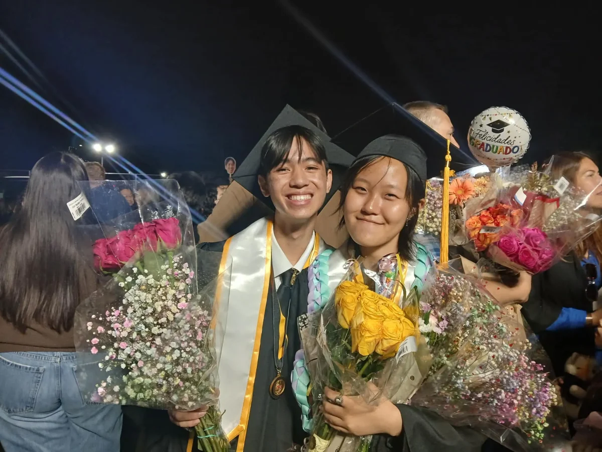 Seniors Zion Borriboonratana and Han Song share an emotional moment together after the ceremony. Once seniors were dismissed, students could wear the many leis and boquets their loved ones brought them. Photo taken by Zion Borriboonratana.